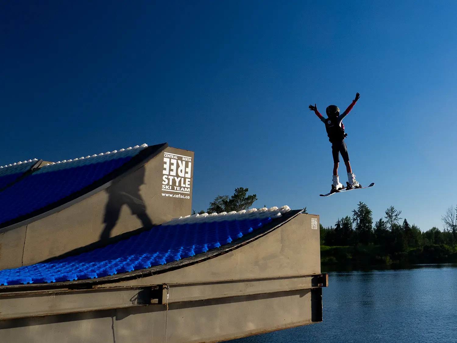 child jumping off a water ramp on skis in Red Deer